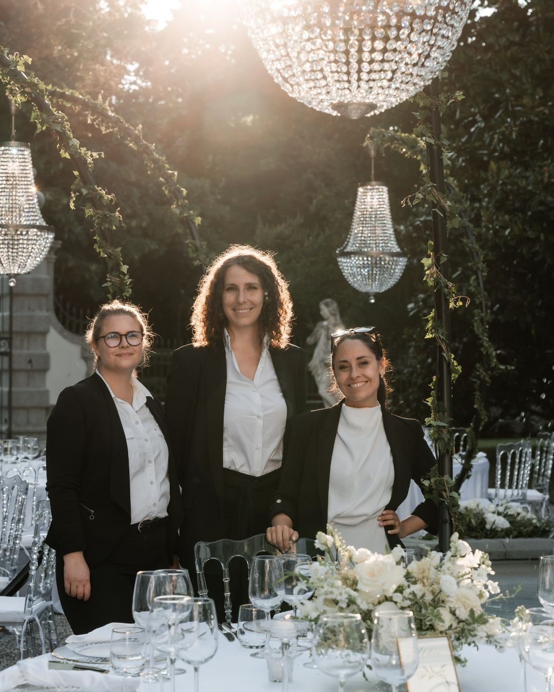 Team di Le Petit O Weddings durante l’allestimento di un matrimonio elegante all’aperto in Italia, con lampadari di cristallo e tavola apparecchiata