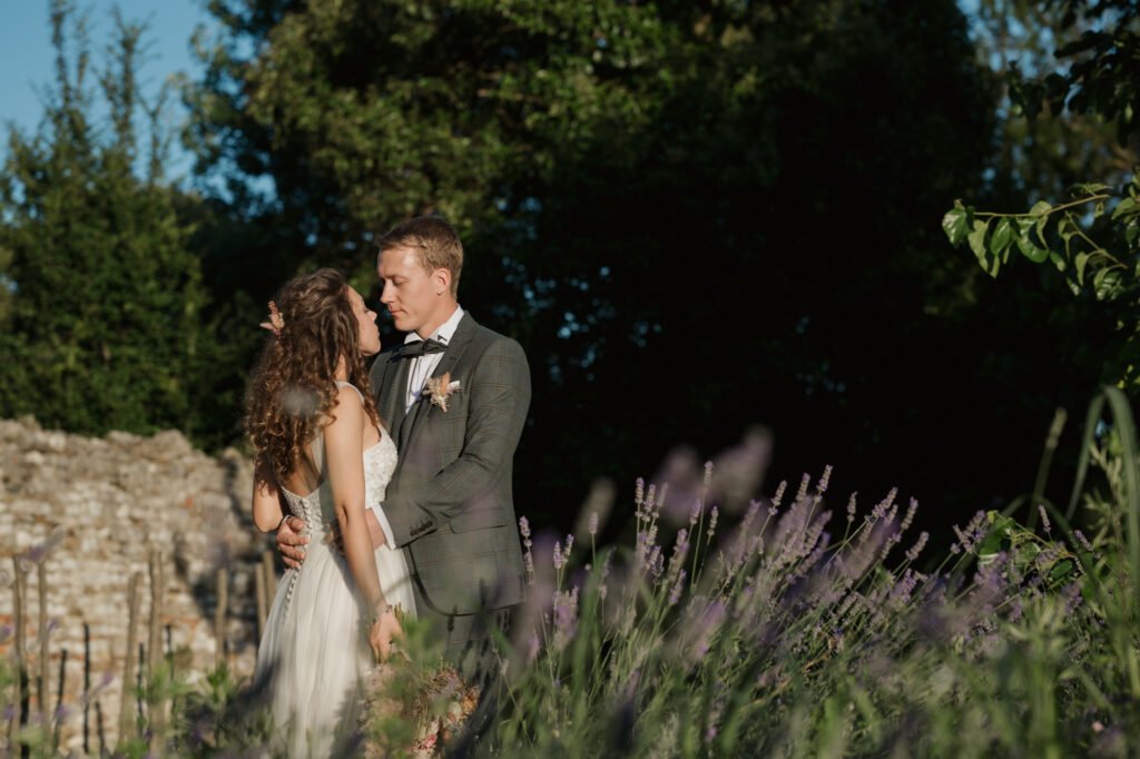 Coppia di sposi abbracciati in un giardino al tramonto, circondati da lavanda e vegetazione naturale