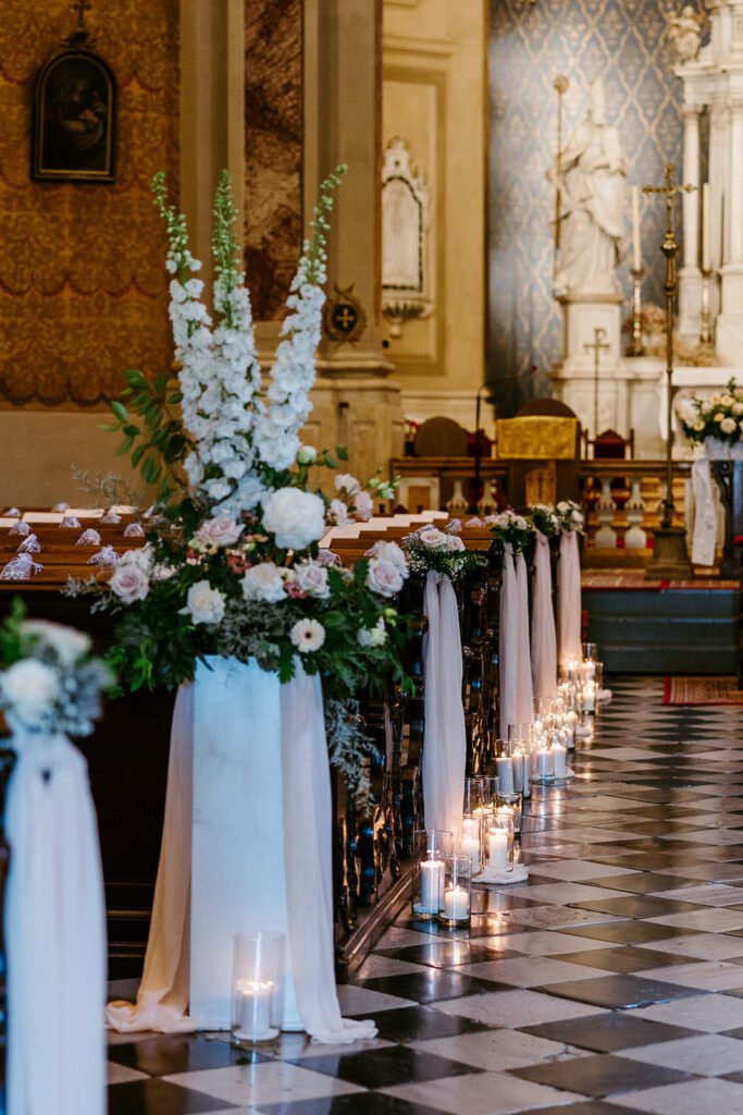 Floral aisle arrangements with candles decorating the church for the wedding ceremony