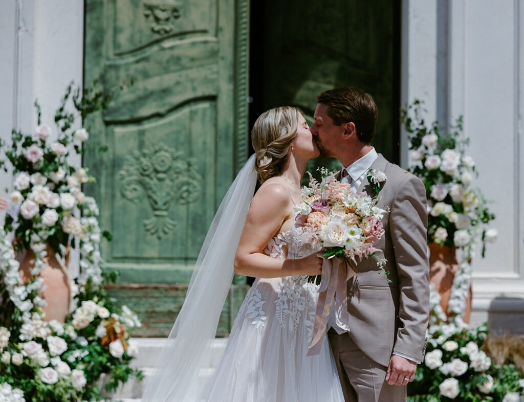Bride and groom leaving the church after their wedding ceremony surrounded by flower petals