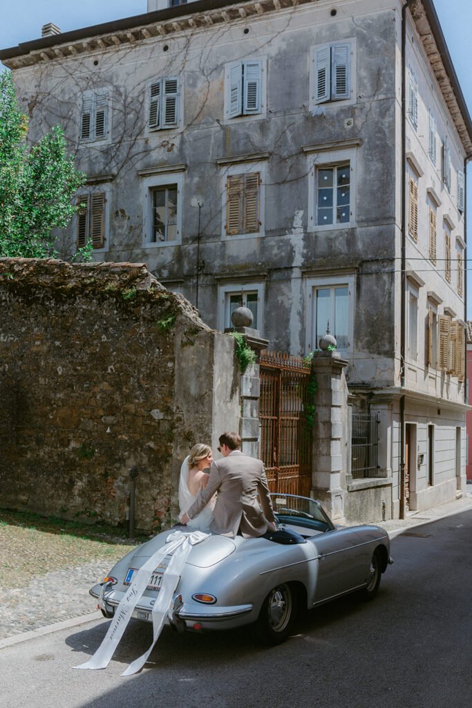 Bride and groom in a vintage Porsche during their wedding in Cormons, Italy