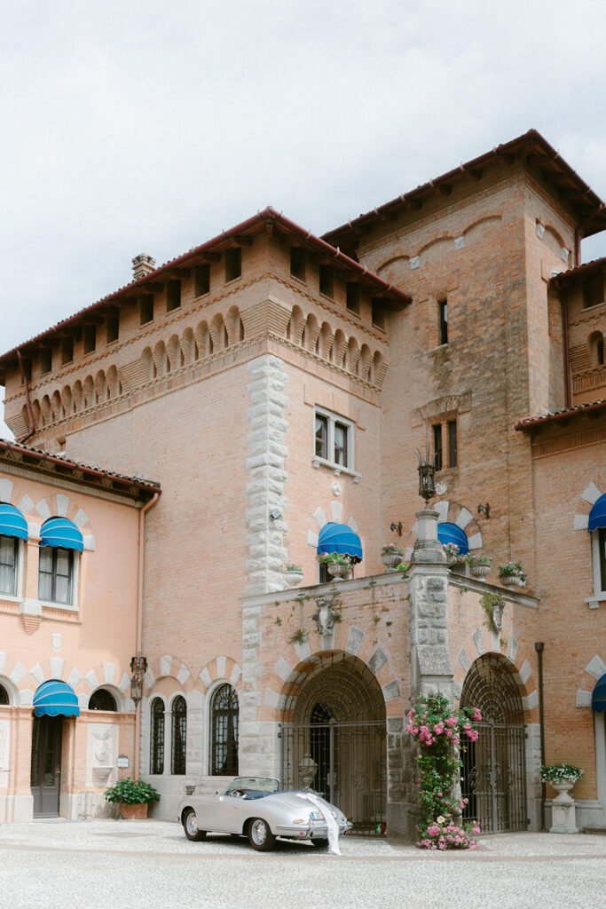 Historic façade of Castello di Spessa with vintage Porsche parked in the courtyard