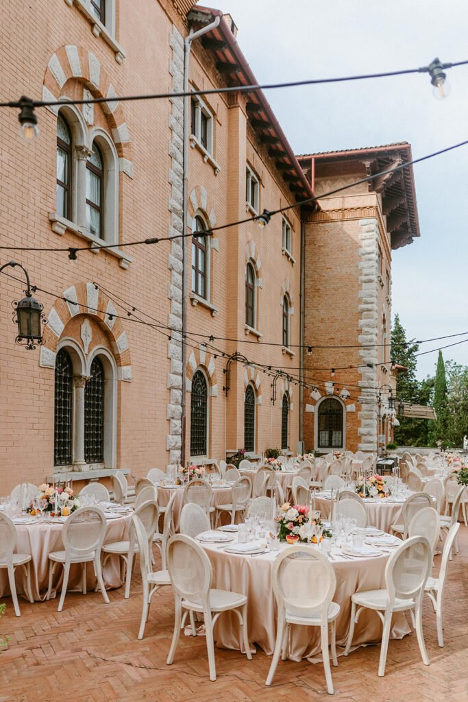 Outdoor wedding reception in the courtyard of Castello di Spessa with elegant round tables