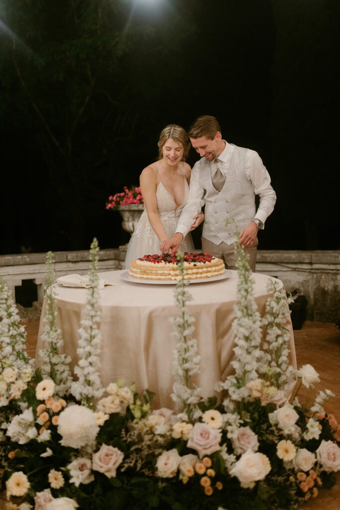 Bride and groom cutting their wedding cake surrounded by romantic floral arrangements