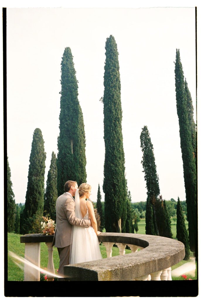 Bride and groom embracing on the panoramic terrace overlooking the gardens